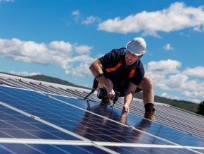 A contractor wearing a safety helmet fixing solar panels to a roof