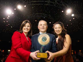 Three winners of a 2023 award holding their trophy to the camera on the awards stage