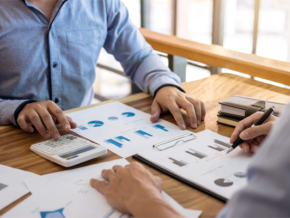 2 people inspecting pages of graphs and charts