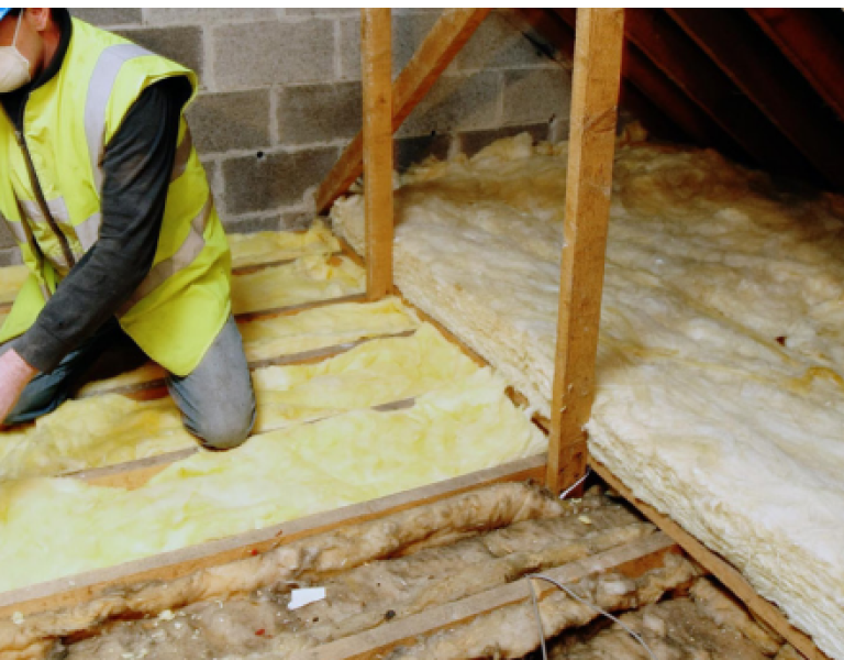 Worker fitting Insulation in an attic.