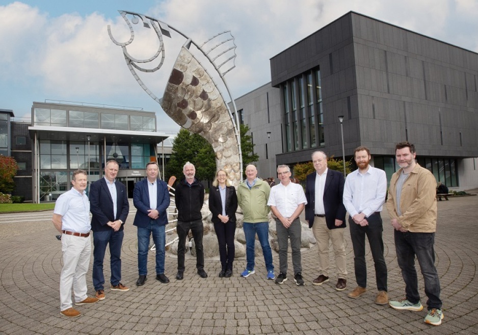 A group of URL people standing infront of a fish sculpture