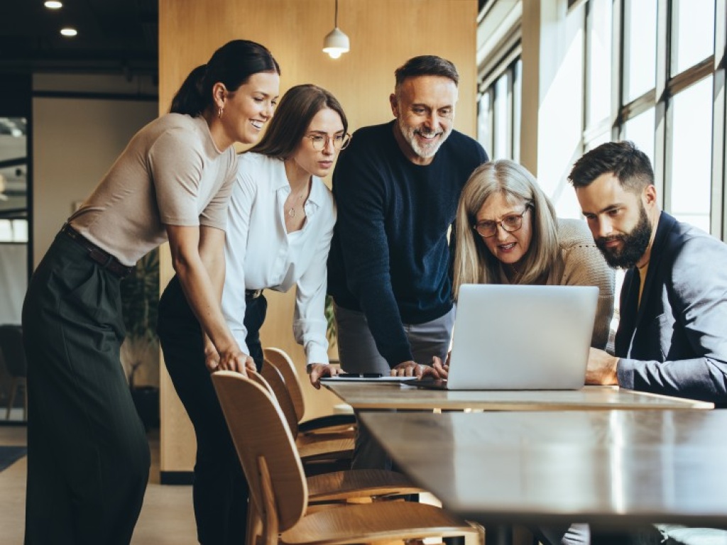 A group of people in a circle looking at a laptop screen