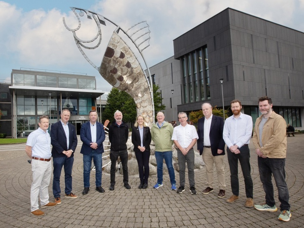 A group of URL people standing infront of a fish sculpture